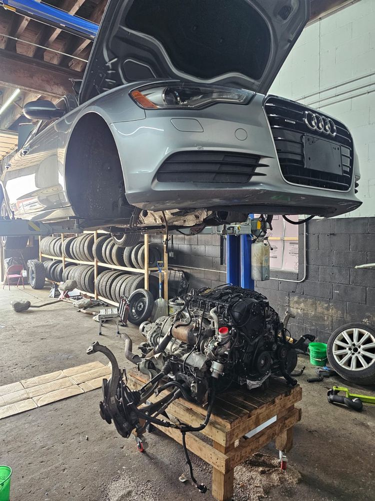 Car on a lift with its engine out on a cart